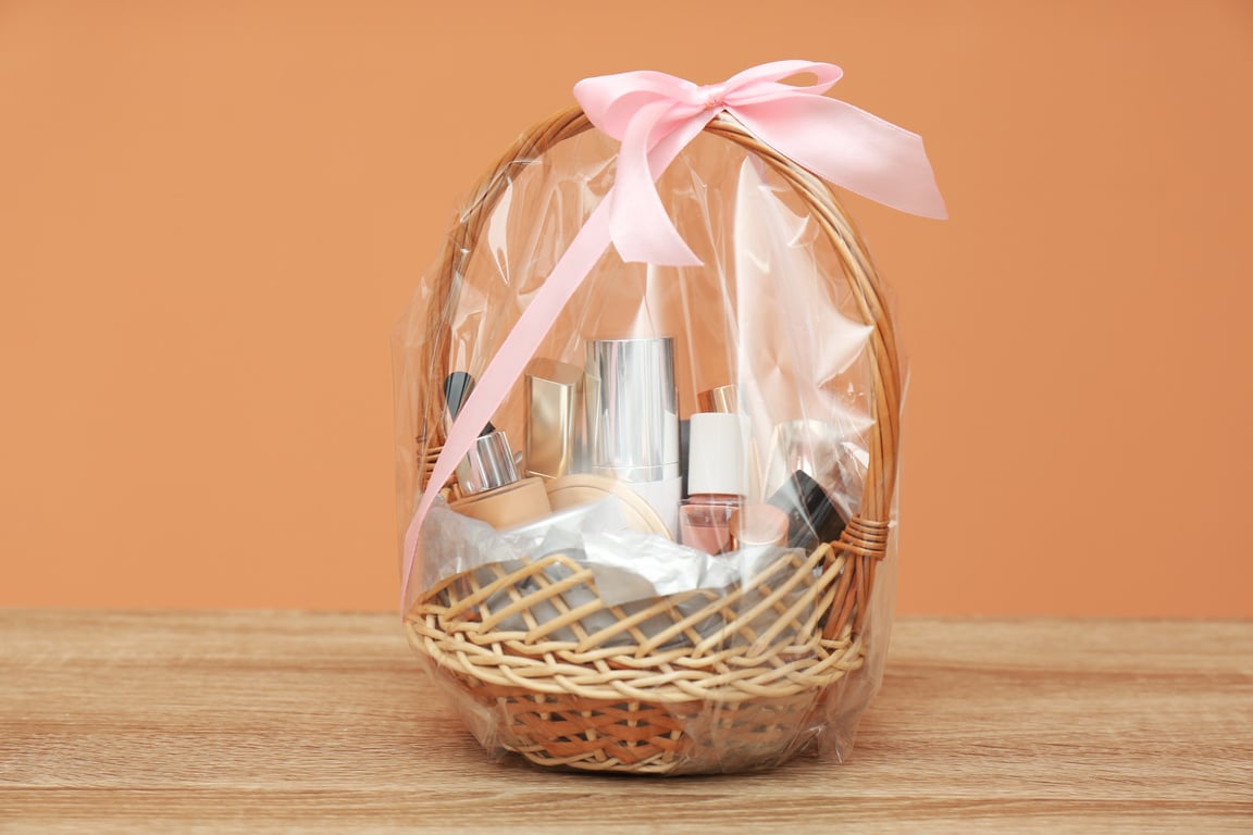 Wicker Gift Basket with Cosmetic Products on Wooden Table